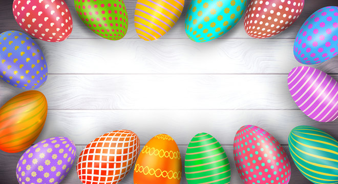 Frame border from colorful Easter eggs on wooden background. Top view. Copy space