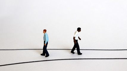 Miniature people walking in different directions. 