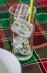Ice in the glass with dish and straw on the table