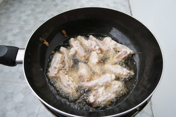 Chicken frying in a pan closeup, boiling oil.