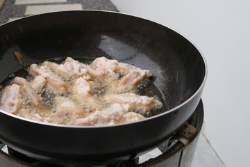 Chicken frying in a pan closeup, boiling oil.