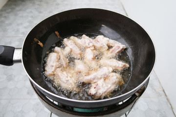 Chicken frying in a pan closeup, boiling oil.