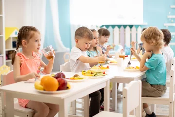 Tuinposter Group of children eating healthy food in day care centre © Oksana Kuzmina