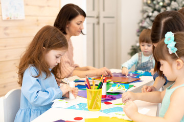 Group of kindergarten children at daycare. Preschool children working with color paper, sciccors and glue on art class in classroom