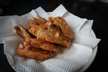 The fried chicken wings are placed on a plate that is covered with tissue paper.