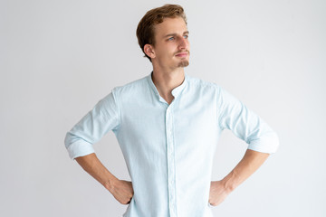 Obraz premium Thoughtful man looking away and holding hands on hips