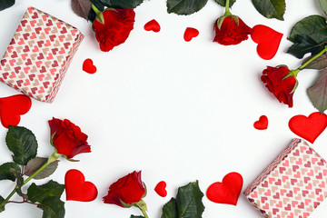 Romantic frame of gifts, rose flowers and decorative hearts on white background. Place for text, top down composition.