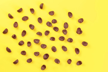 Top down view, chocolate cornflakes scattered on yellow board.