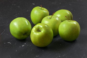 Green / yellow apples on black marble board.