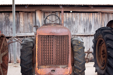 Old rusted farm tractor, grille closeup, antique machinery, with rough wooden shed wall in...