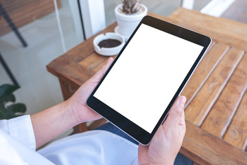 Mockup image of a woman holding black tablet pc with blank white screen while sitting
