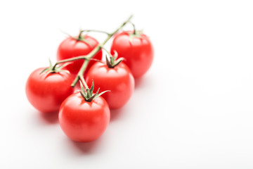 A branch of cherry tomato lies on a white surface.