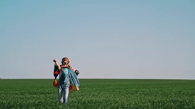 Kid with jet pack outdoor. Child playing in green spring field