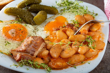 Eating beans with smoked pork meat, eggs