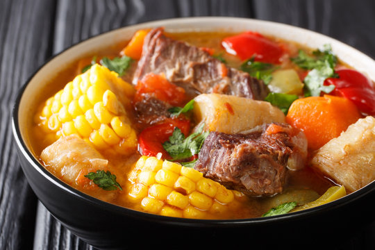 Latin American Sancocho thick meat soup with vegetables close-up on a plate on the table. horizontal