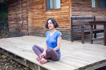 A woman is sitting on the porch of an old wooden house.