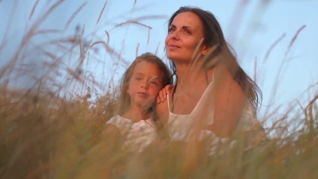 mother and little daughter are relaxing in the evening field, family in nature