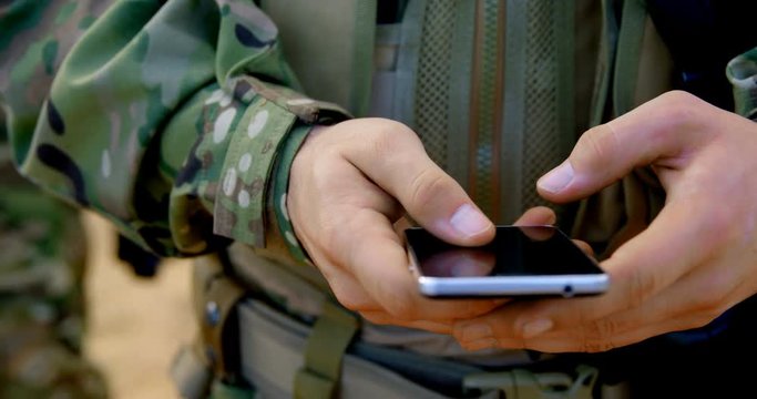 Mid section of caucasian military soldier using mobile phone during military training 4k