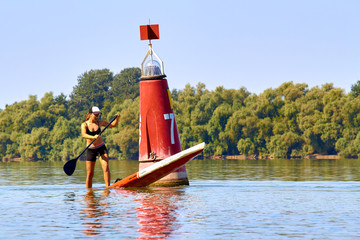Athletic girl with perfect body standing with a paddle on the stand up paddle board (paddleboard,...
