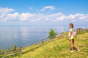 Laughing teenage girl standing on the steep bank of the river