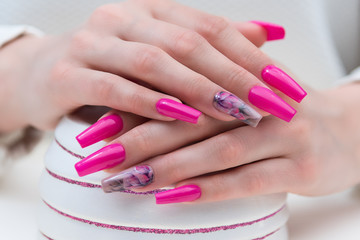 Fashionable manicure nail art. Woman hands on white ceramic vase.