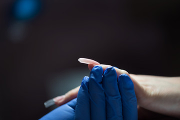 Woman polishing fingernails with nail file on manicure treatment in beauty salon