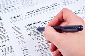 Tax reporting. Human fills out the 5304-simple tax form on background other forms