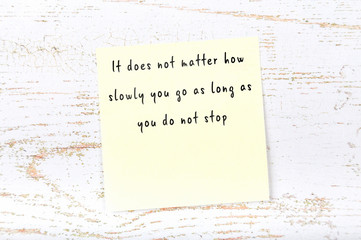 Positive inspiring quote handwritten on sticky note on wooden background
