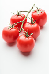 A branch of cherry tomato lies on a white surface.