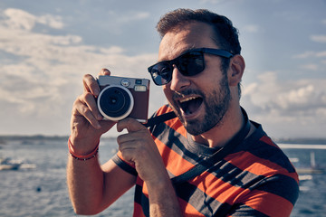 Obraz premium Man using vintage film camera on a ocean / sea vacation.