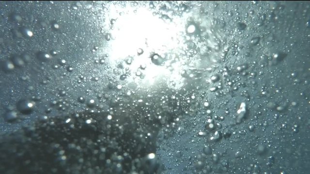 Man's hand asking for help underwater with air bubbles in sunlight, male slowly rise up and survive. Concept of drowning in deep sea, moment of salvation