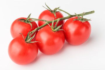 A branch of cherry tomato lies on a white surface.