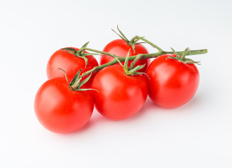 A branch of cherry tomato lies on a white surface.