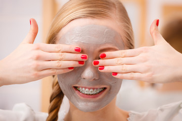 Happy young woman having mud mask on face