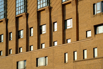 Building pattern beautiful architecture in yellow or brick color sunrise along many glasses window surrounding the building , nice background design.