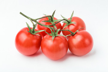 A branch of cherry tomato lies on a white surface.