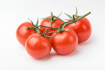 A branch of cherry tomato lies on a white surface.