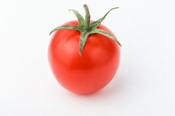 One cherry tomato lies on a white surface.