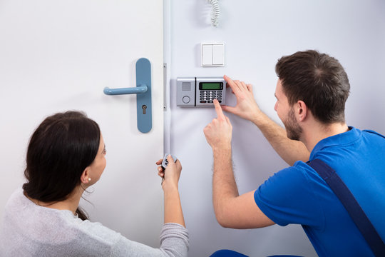 Handyman Installing Security System Near Door Wall