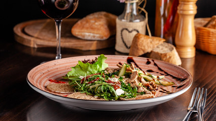 European Italian cuisine. Warm salad of veal, fried arugula, cucumber, mix lettuce, dried tomatoes, sweet peppers and cheese dorblu. Red wine.  background image. copy space