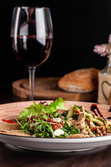 European Italian cuisine. Warm salad of veal, fried arugula, cucumber, mix lettuce, dried tomatoes, sweet peppers and cheese dorblu. Red wine.  background image. copy space