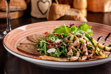 European Italian cuisine. Warm salad of veal, fried arugula, cucumber, mix lettuce, dried tomatoes, sweet peppers and cheese dorblu. Red wine.  background image. copy space