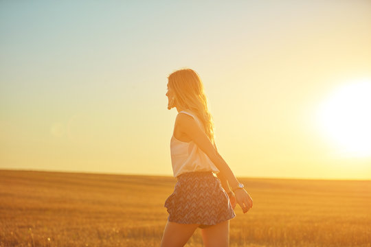 Cute young woman jumping in a wheat field.