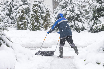 Fototapeta premium Man removing snow from the sidewalk after snowstorm.