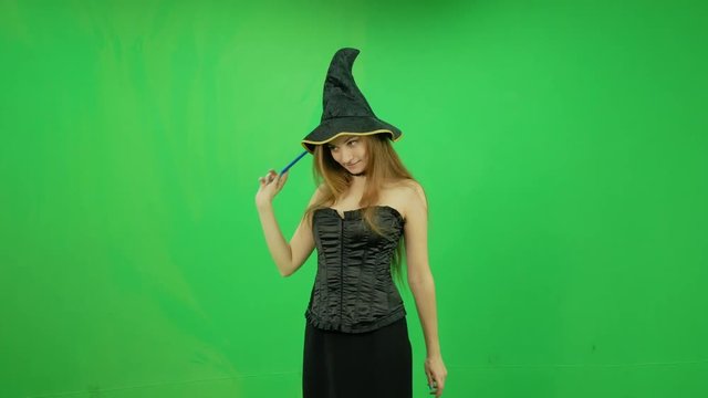 Beautiful funny witch casting spell and smiling at green screen
