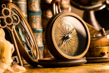 Antique compass on the background of a candle with a key and books. Vintage style. 1565 old map of the year.