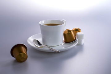 Studio shot of a cup of expresso coffee with coffee capsules and sugar lumps.
