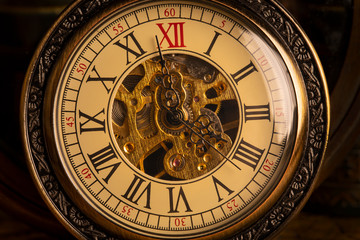 Fototapeta na wymiar Antique clock on the background of vintage books. Mechanical clockwork on a chain.