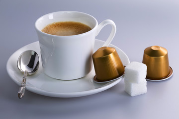 Studio shot of a cup of expresso coffee with coffee capsules and sugar lumps.