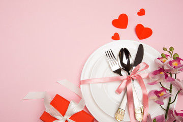Festive table setting for Valentine's Day with fork, knife,  hearts on a red background. Top view. - Image.